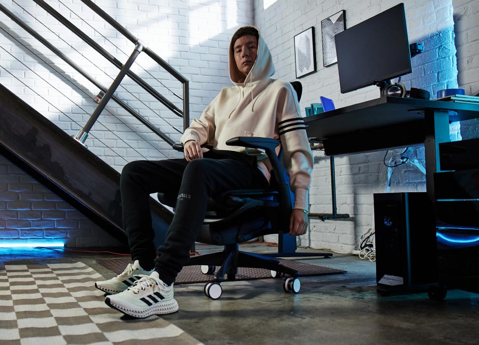 Kuva G2 Esports -tiimin Jelty istumassa G2 Embody -tuolissa selkä pelikokoonpanoon päin, jossa on musta Nevi-pelipöytä ja Ollin-näytöt