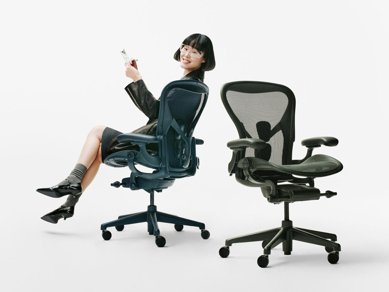Valkoisessa studiossa istui nainen Nighfall-sinisellä Herman Miller Aeron -ergonomisella työtuolilla toisen, Jasper-vihreän Aeron-tuolin vieressä.