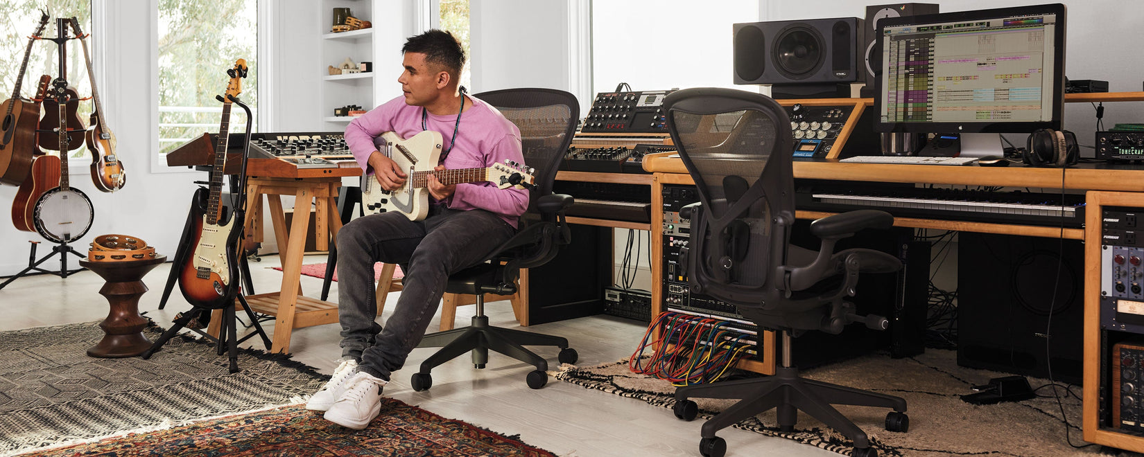Rostam Batmanglij, muusikko, tuottaja ja säveltäjä, soittaa Italia Modena Electric Sitar -kitaraa musiikkistudiossaan istuen grafiittivärisessä Aeron-työtuolissa.