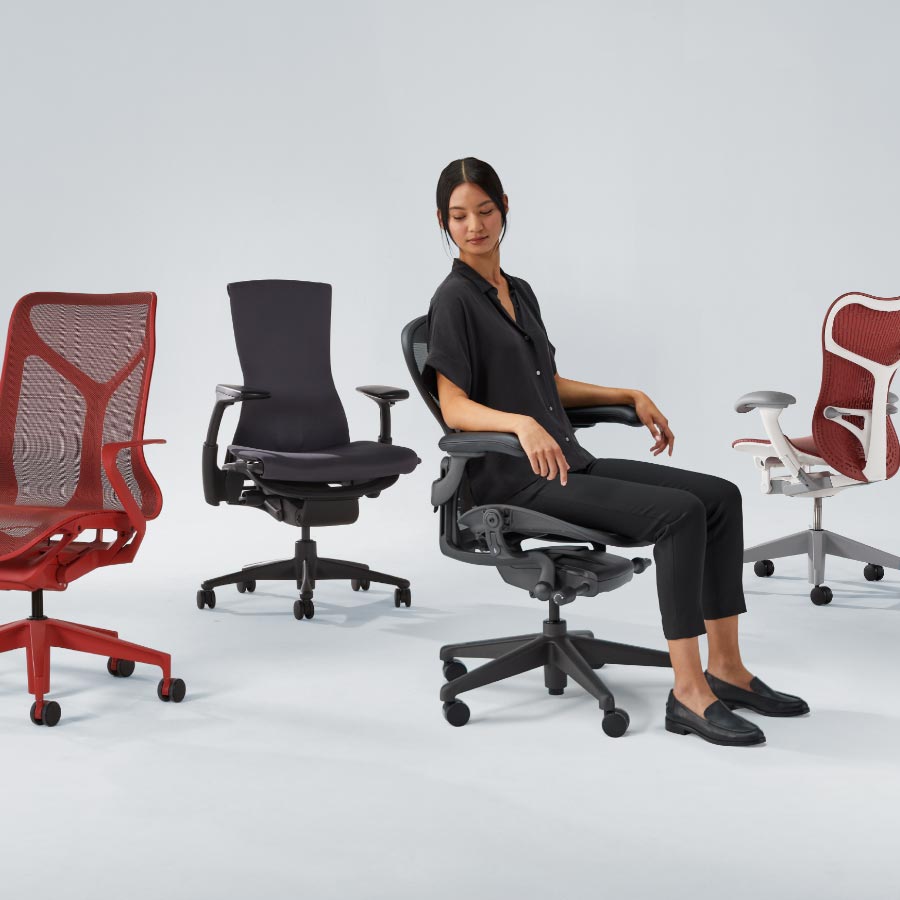 Neljän Herman Miller -työtuolin rivistö, jossa Cosm-tuoli keskikorkealla selkänojalla kanjoninpunaisena, Embody-tuoli mustana, Aeron-tuoli grafiitinvärisenä naisen istuessa ja lopuksi Mirra 2 -tuoli valkoisella rungolla ja punaisella istuimella ja selkänojalla