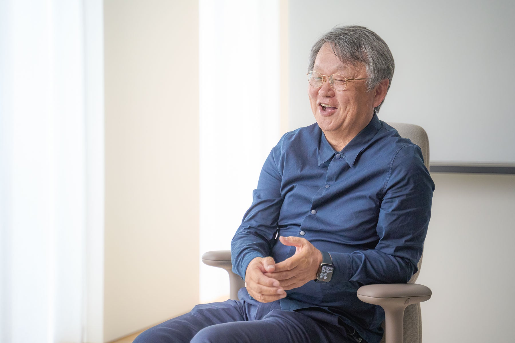 Iloinen valokuva Naoto Fukasawasta istumassa Asari-työtuolissa
