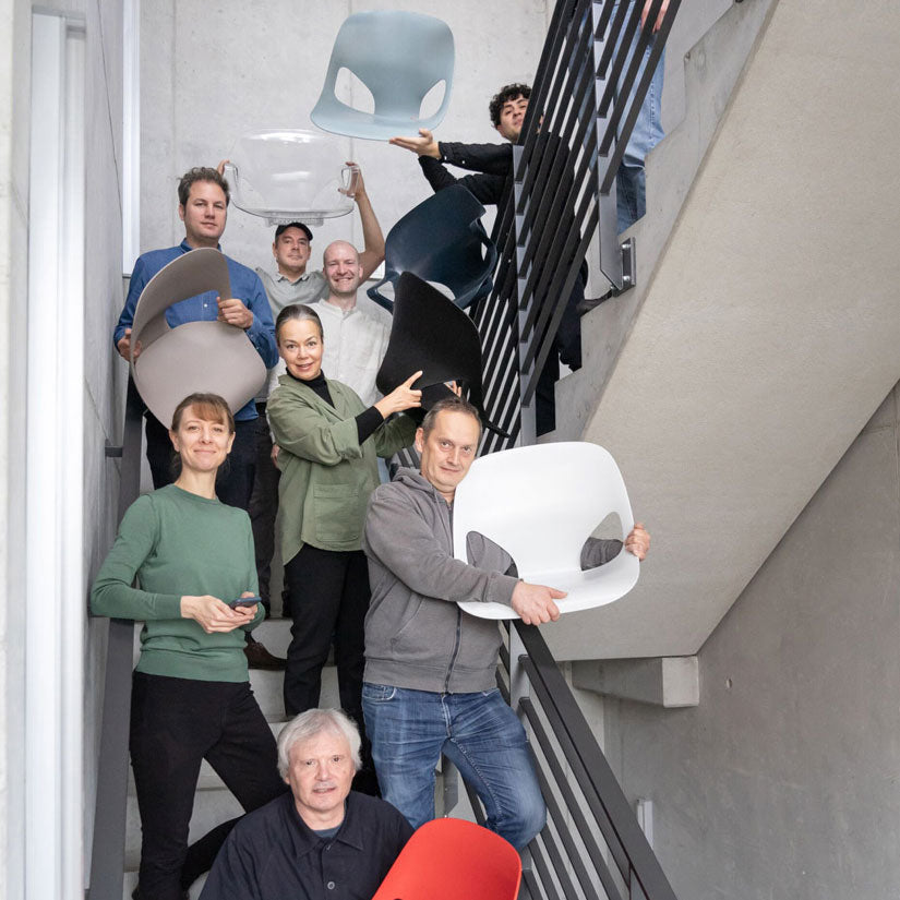 Valokuva Studio 7.5 -suunnittelutiimin jäsenistä portaikossa, jossa he pitävät käsissään suunnittelemiaan Herman Zeph -tuolin osia.